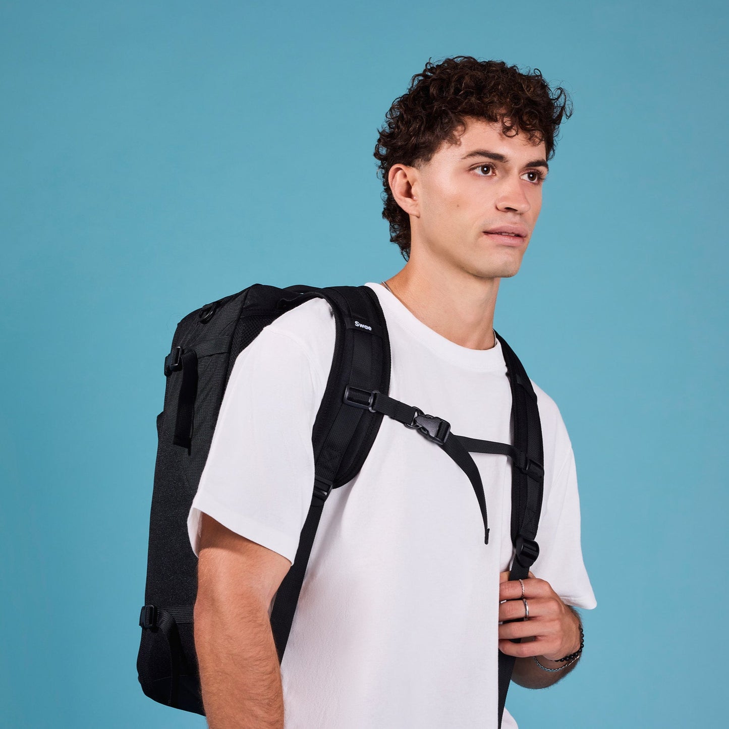 Male traveler wearing the Swae Flow 40L Travel Backpack with the chest strap fastened, providing ergonomic weight distribution and enhanced comfort for extended wear.