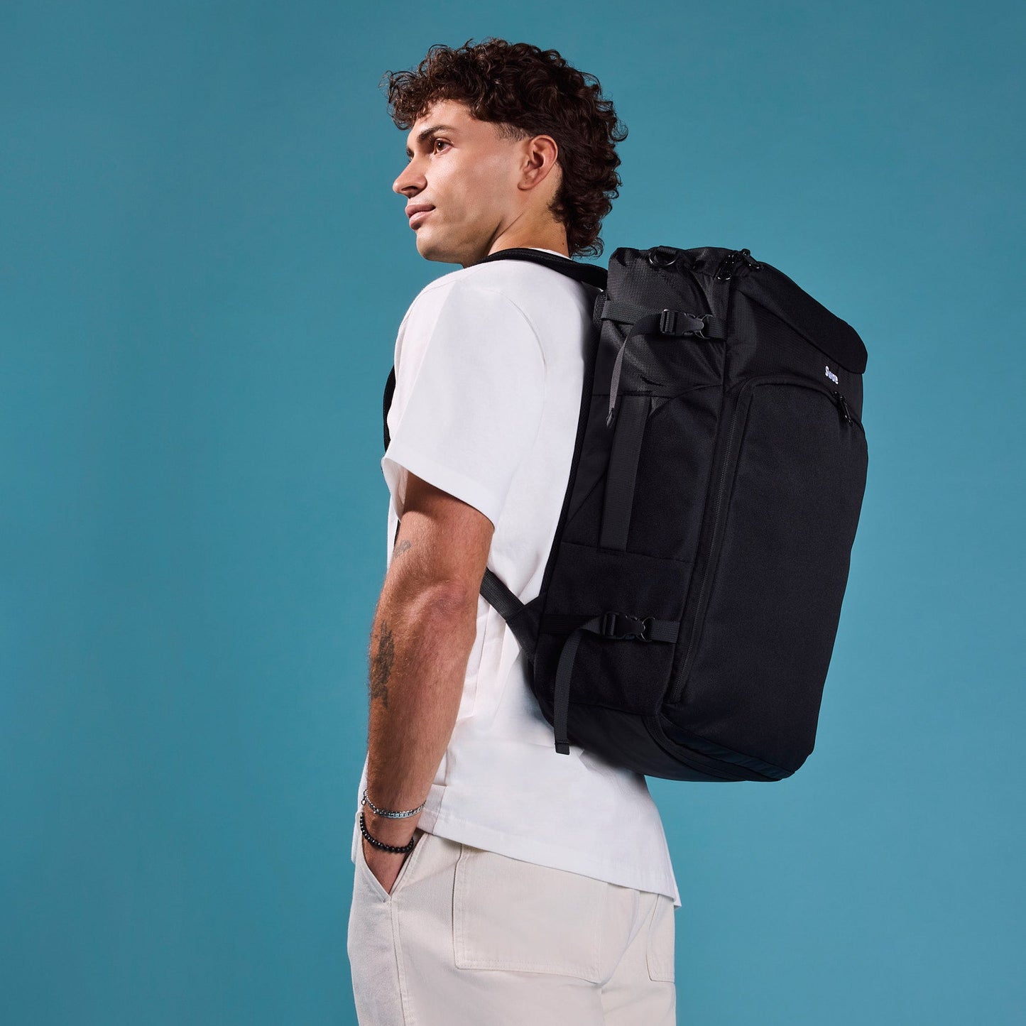 Male traveler walking with the Swae Flow 40L Travel Backpack, a versatile carry-on designed for seamless city travel, commuting, and international trips.