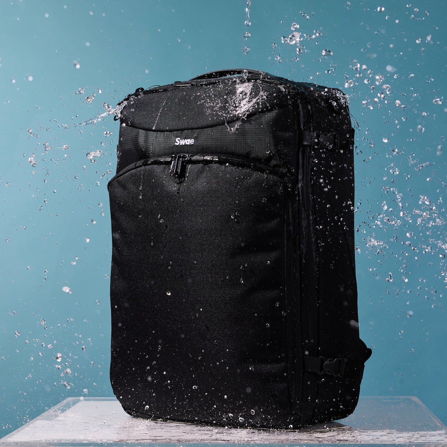Water-resistant Swae Flow 40L Travel Backpack being splashed with water, showcasing its durable, weatherproof recycled RPET fabric.