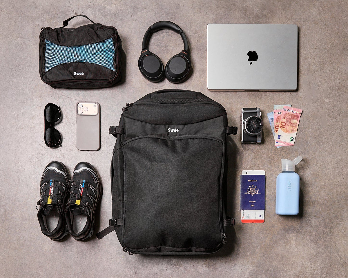 Swae Flow 40L Travel Backpack open with clothing, laptop, shoes and travel essentials laid out for packing