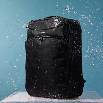 Water-resistant Swae Flow 40L Travel Backpack being splashed with water, showcasing its durable, weatherproof recycled RPET fabric.